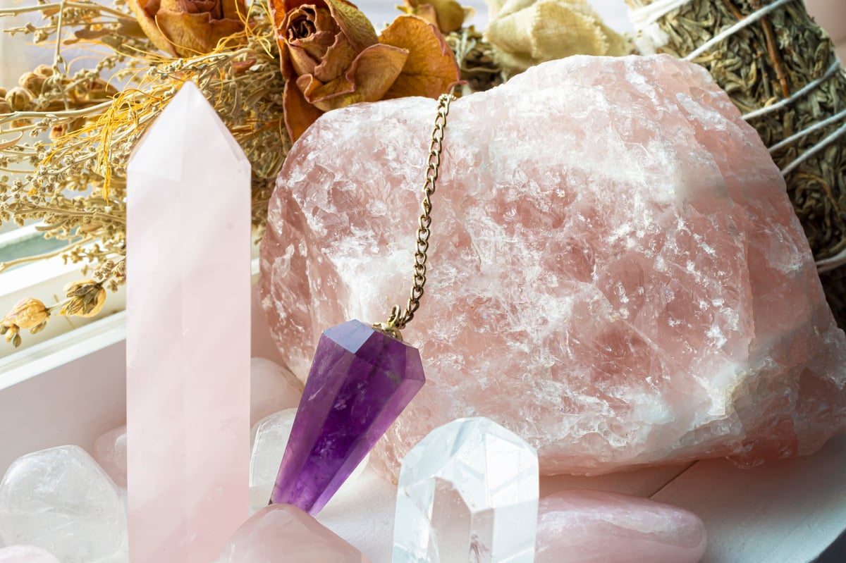 Rose quartz crystals with an amethyst pendulum and sage